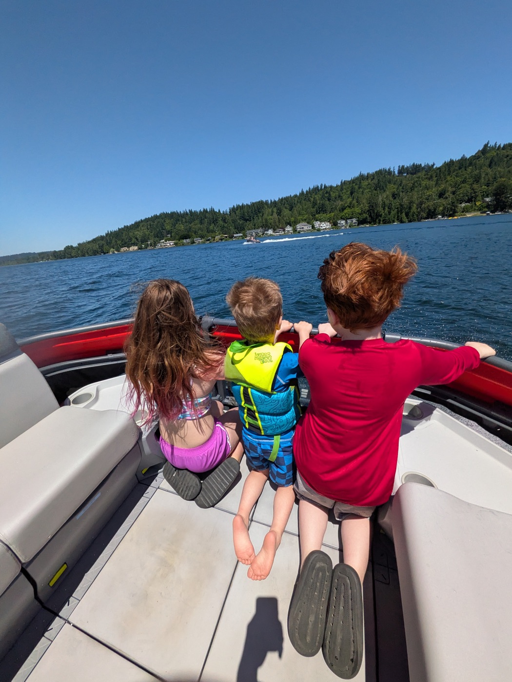 Kids watching the water from the back of the boat